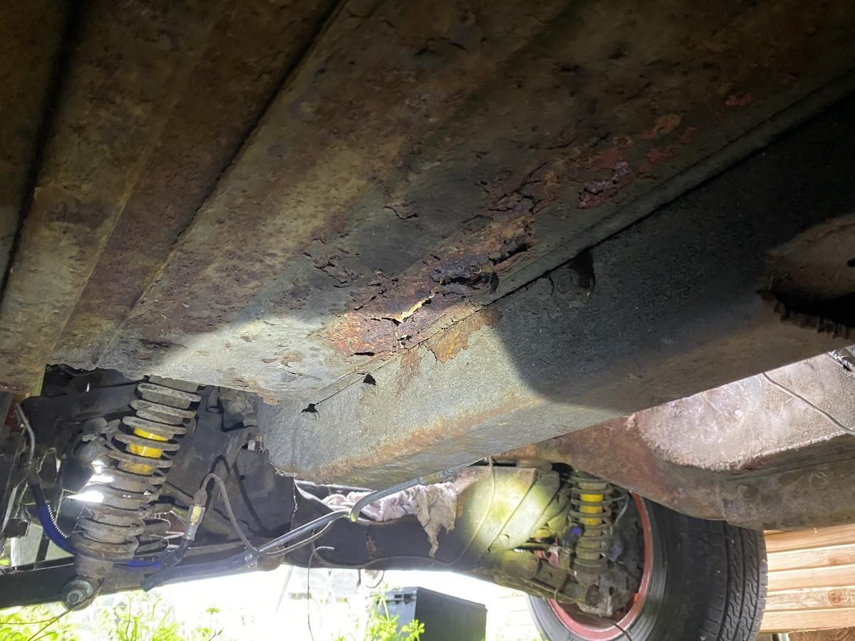 A close up of the underside of a rusty car.