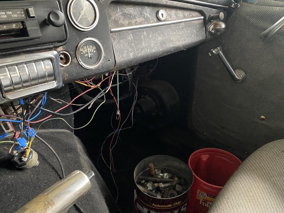 The dashboard of an old car with a lot of wires coming out of it.