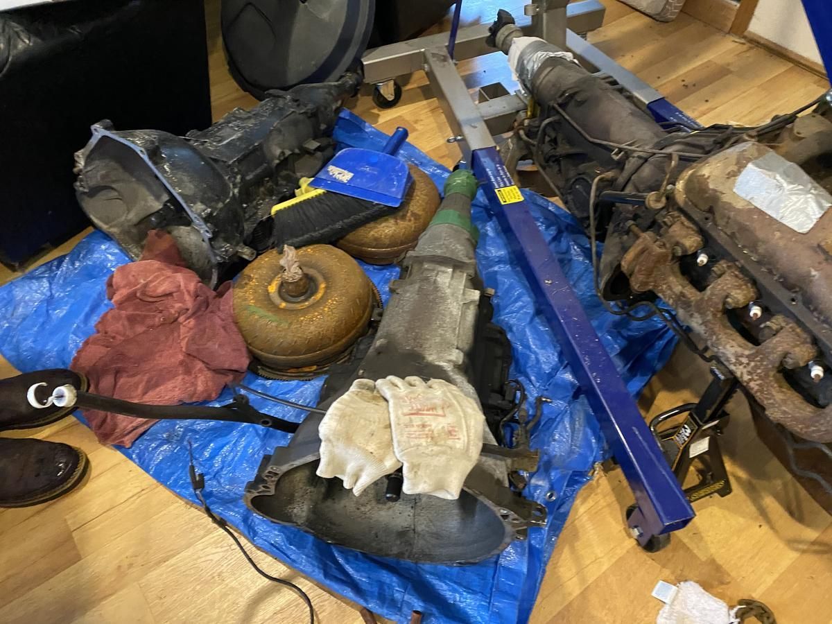 A pile of car parts on a blue tarp on a wooden floor.