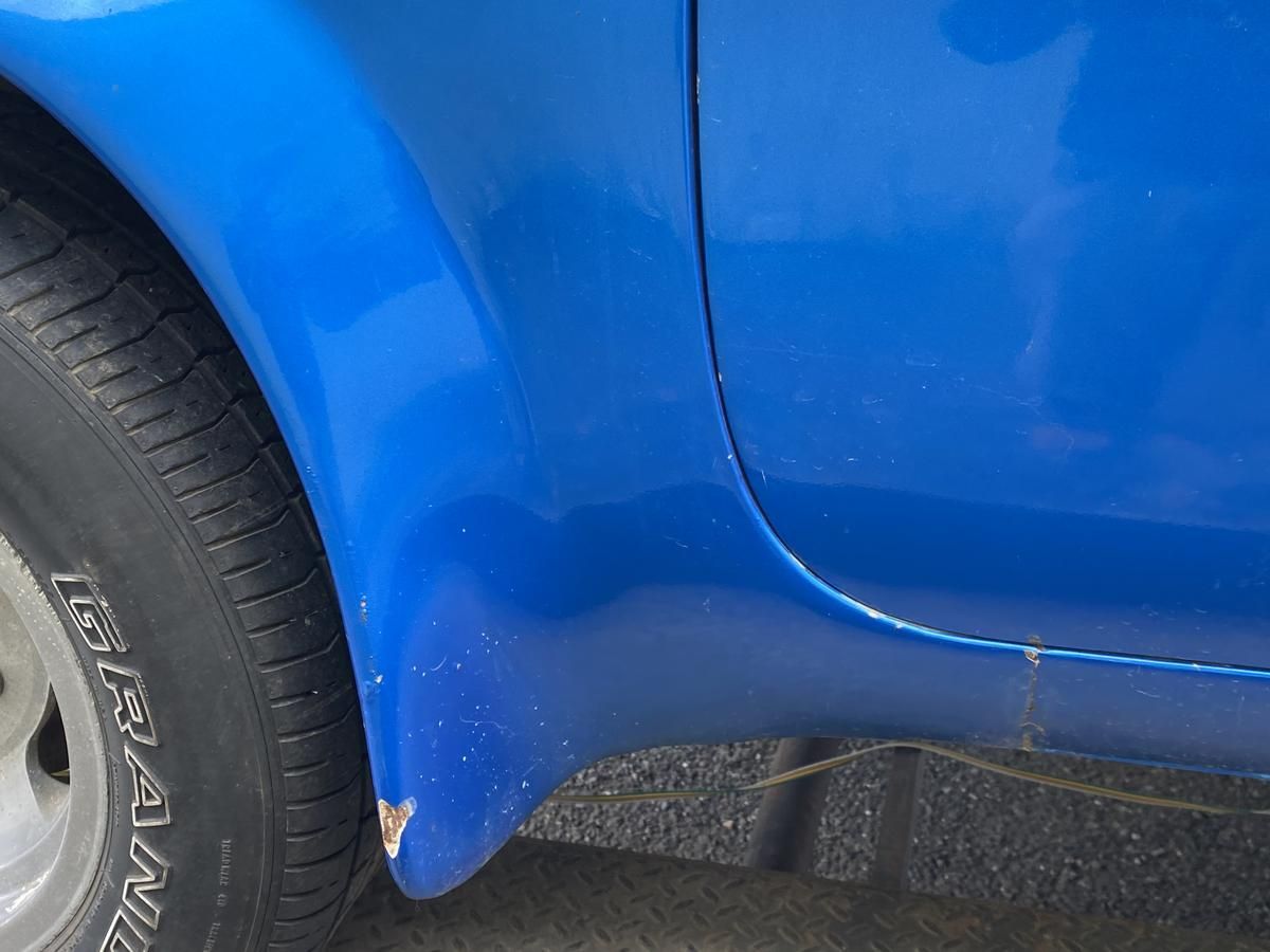 A close up of a blue car 's tire and fender