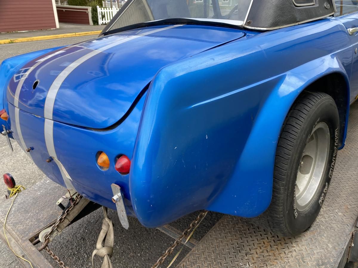 A blue car with a trailer attached to it