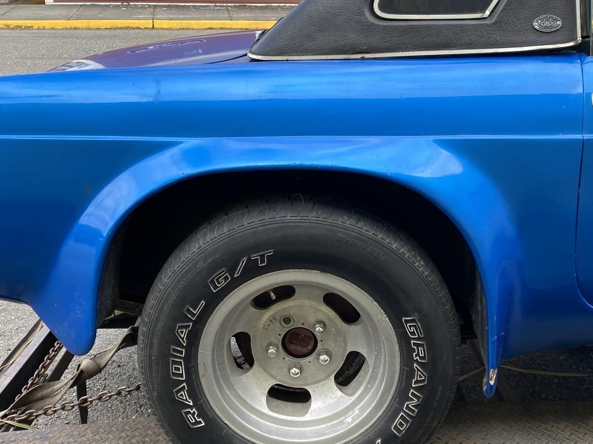 A blue car is parked on the side of the road