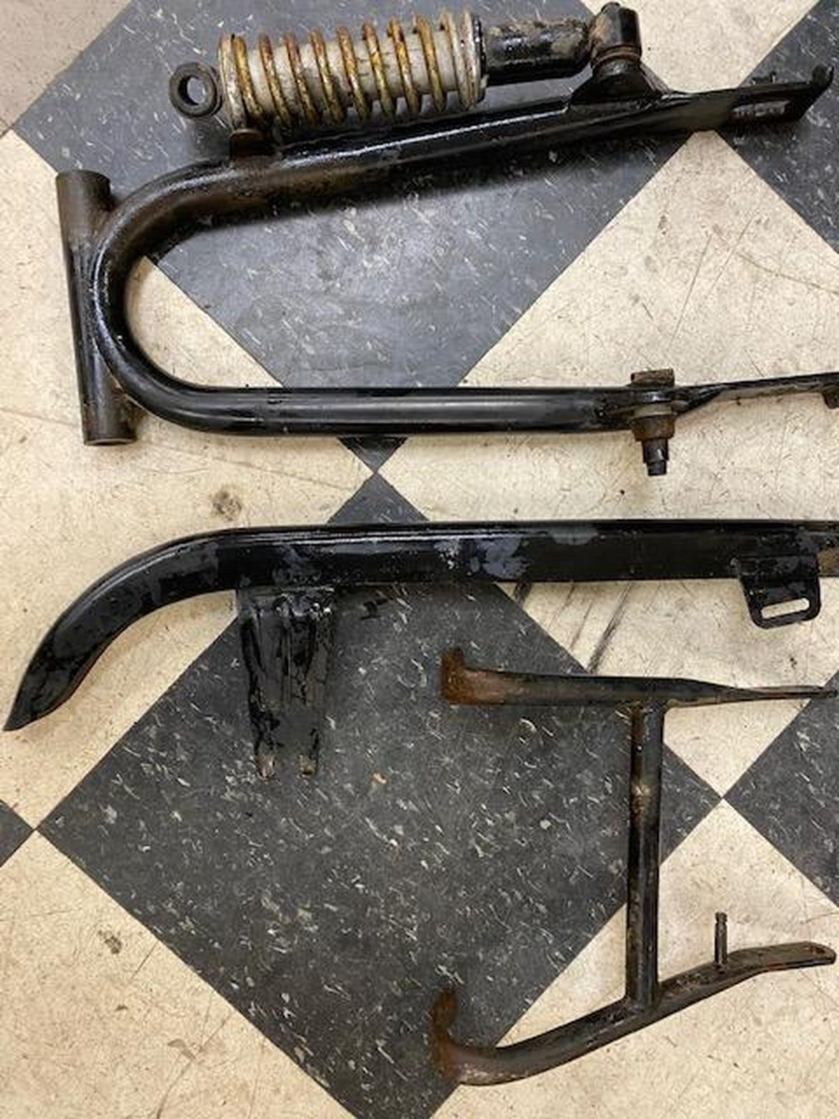 Three pieces of metal are sitting on a checkered floor.
