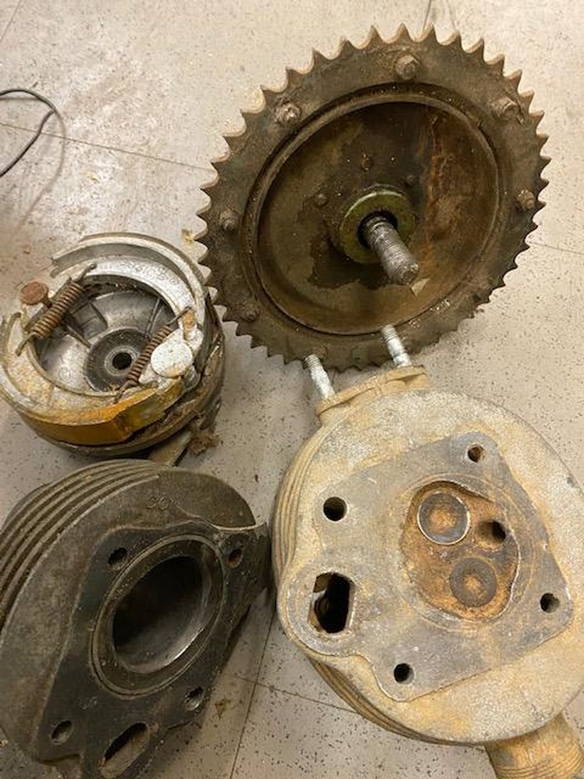 A bunch of old motorcycle parts are sitting on the floor.