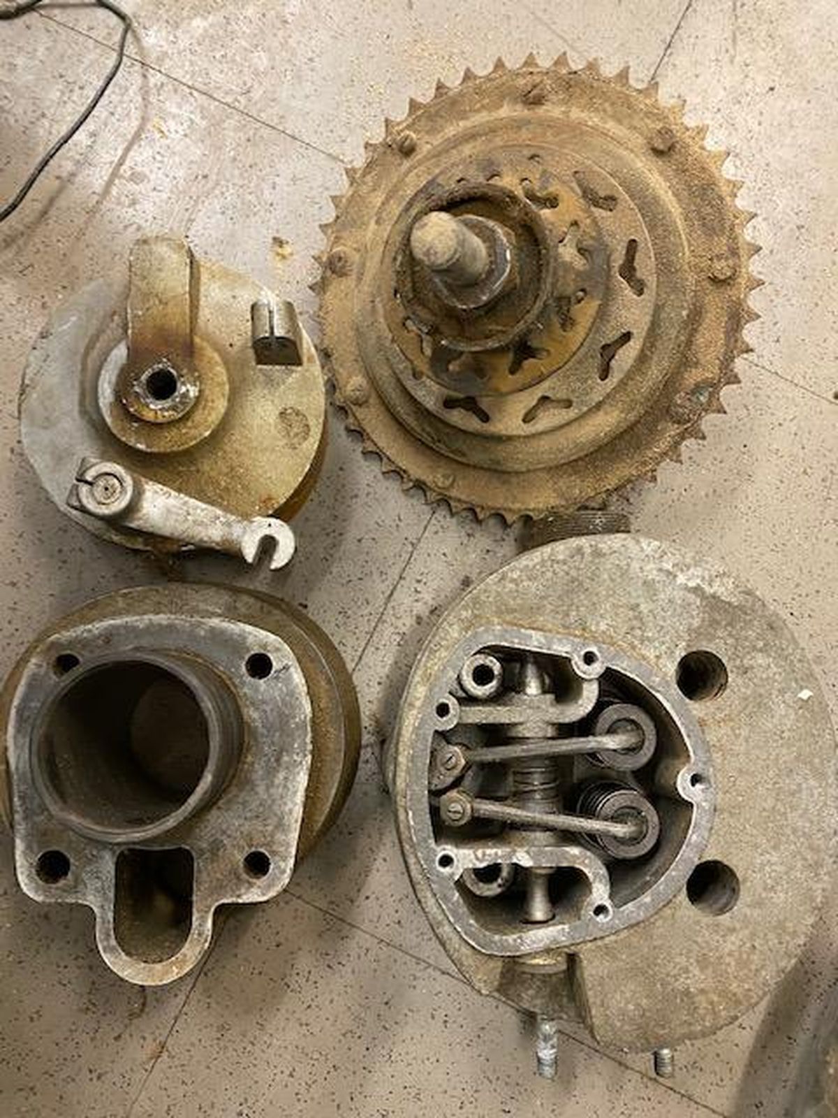 A bunch of old metal parts are sitting on a tiled floor.
