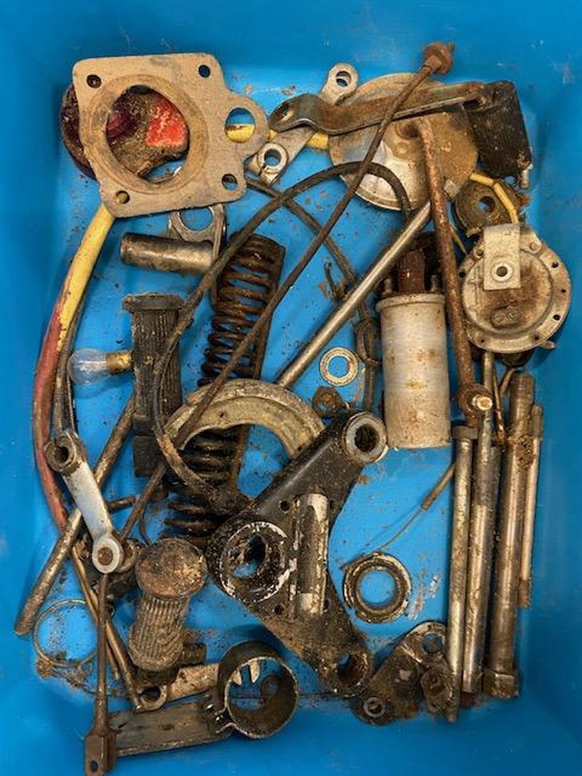 A blue bin filled with lots of rusty metal parts.