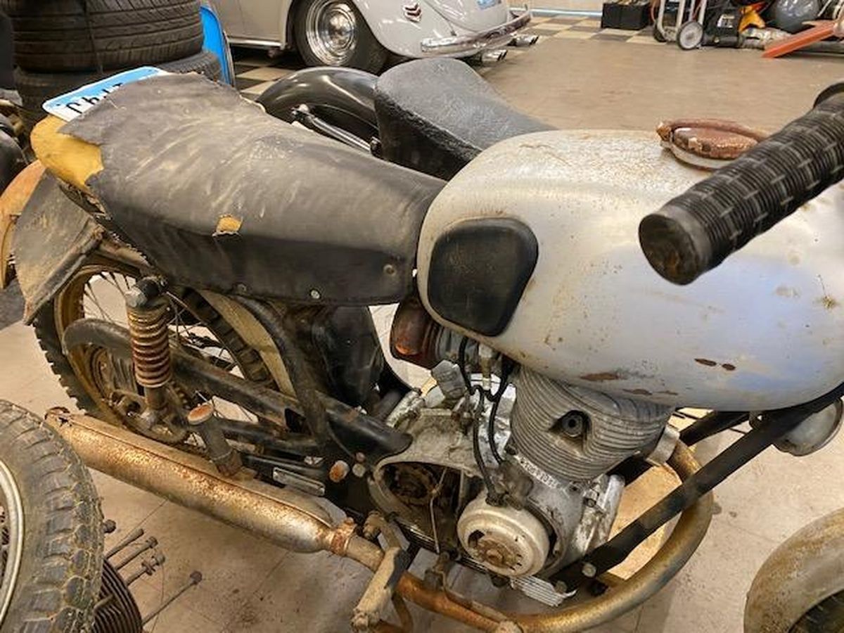 A motorcycle is sitting in a garage next to a car.