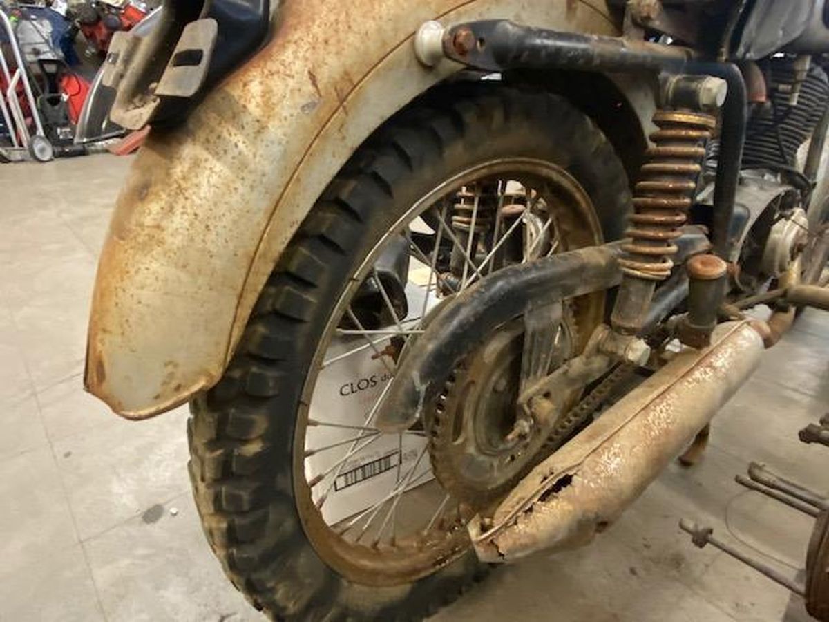 A close up of a motorcycle 's rear wheel and fender in a garage.