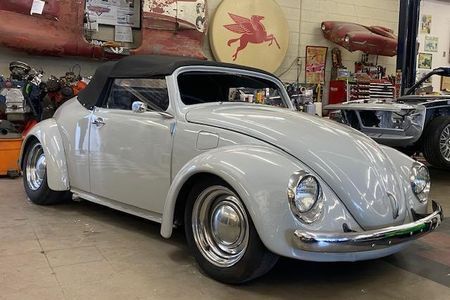 a white volkswagen beetle convertible is parked in a garage .