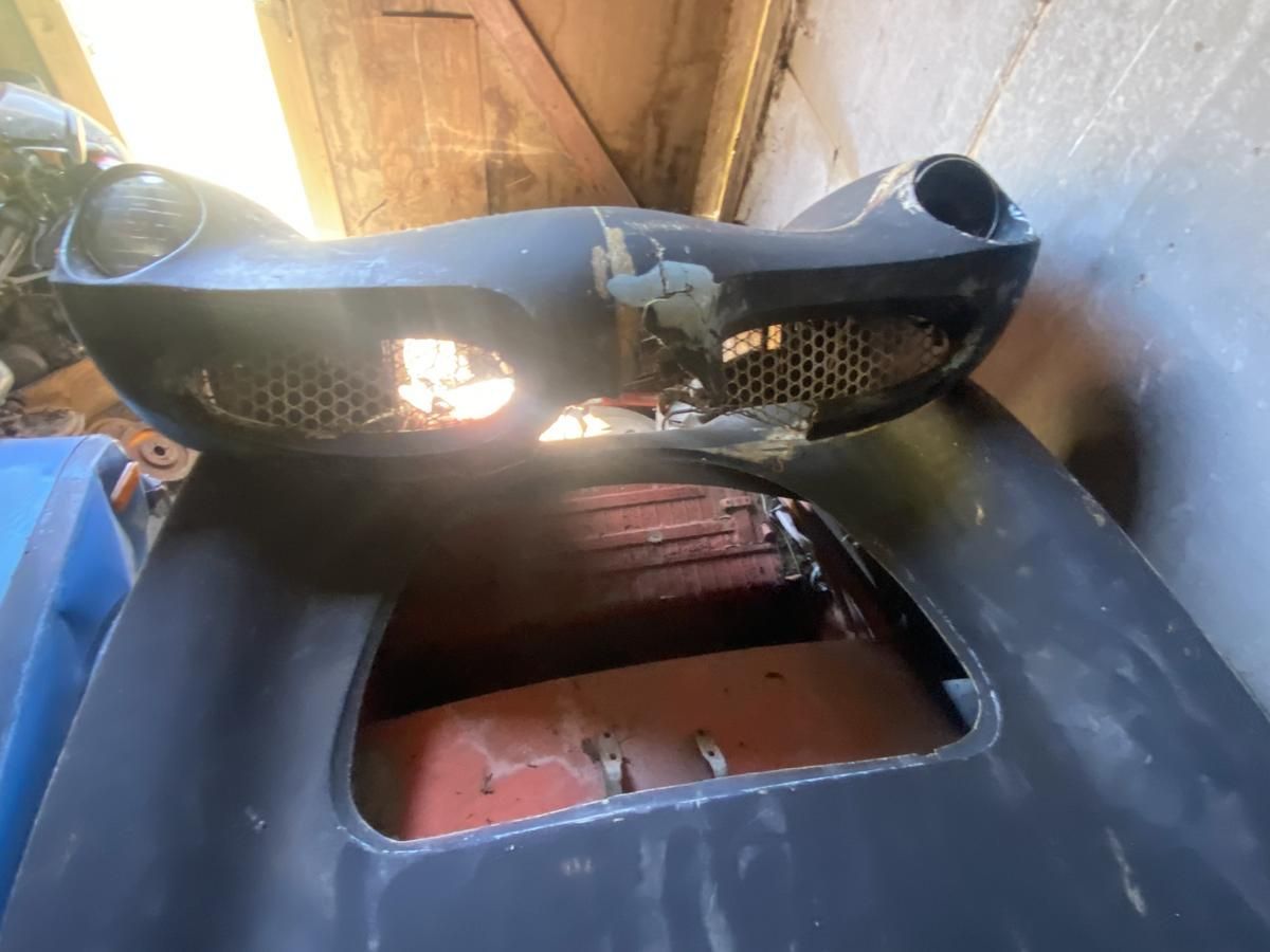 A black car with a broken bumper is sitting in a garage.