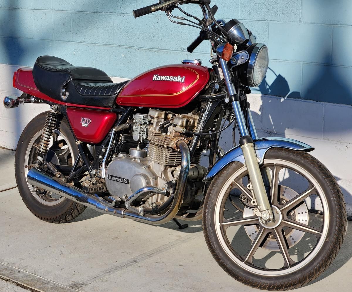 A red kawasaki motorcycle is parked on the sidewalk