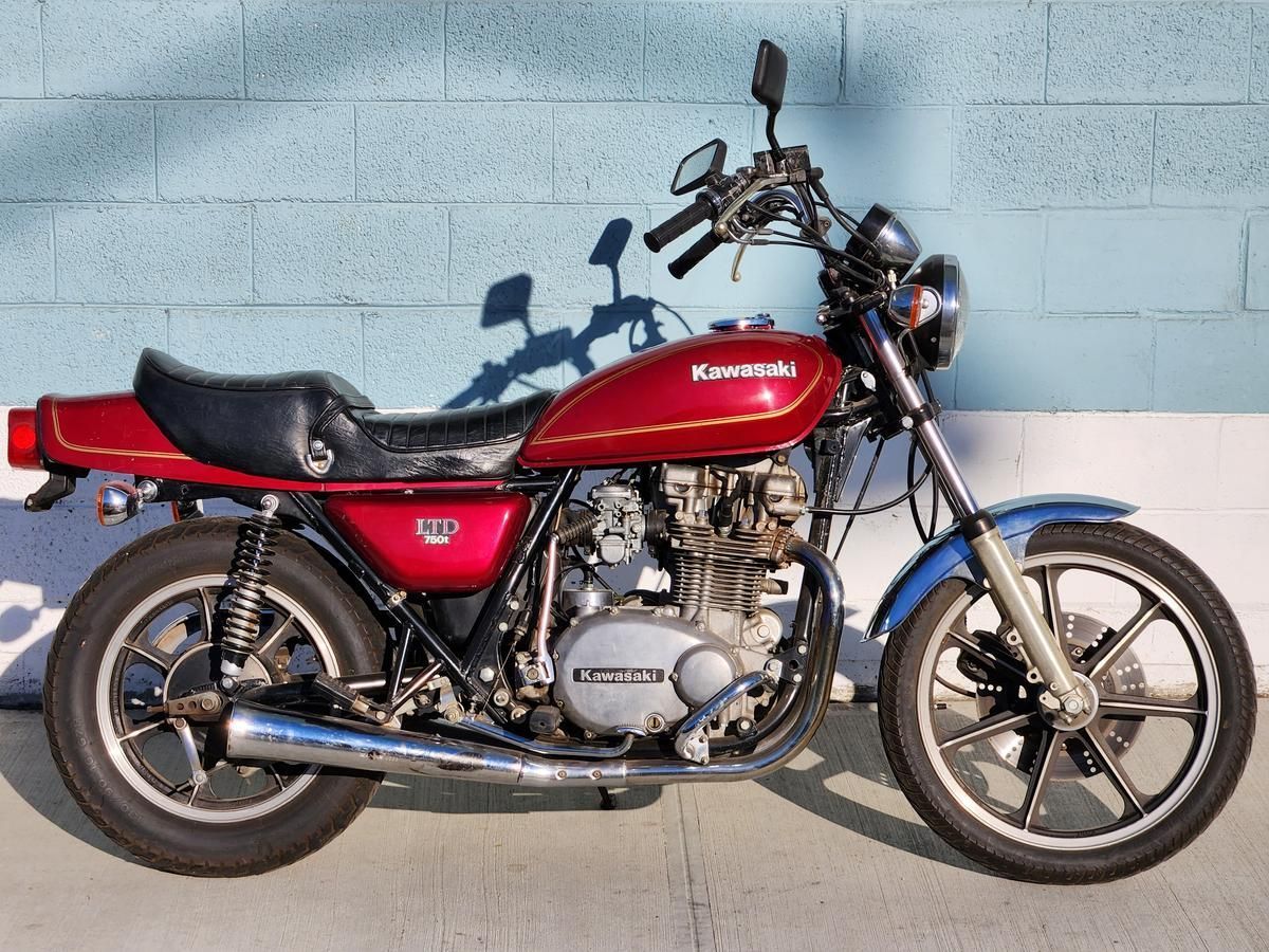 A red kawasaki motorcycle is parked in front of a blue wall