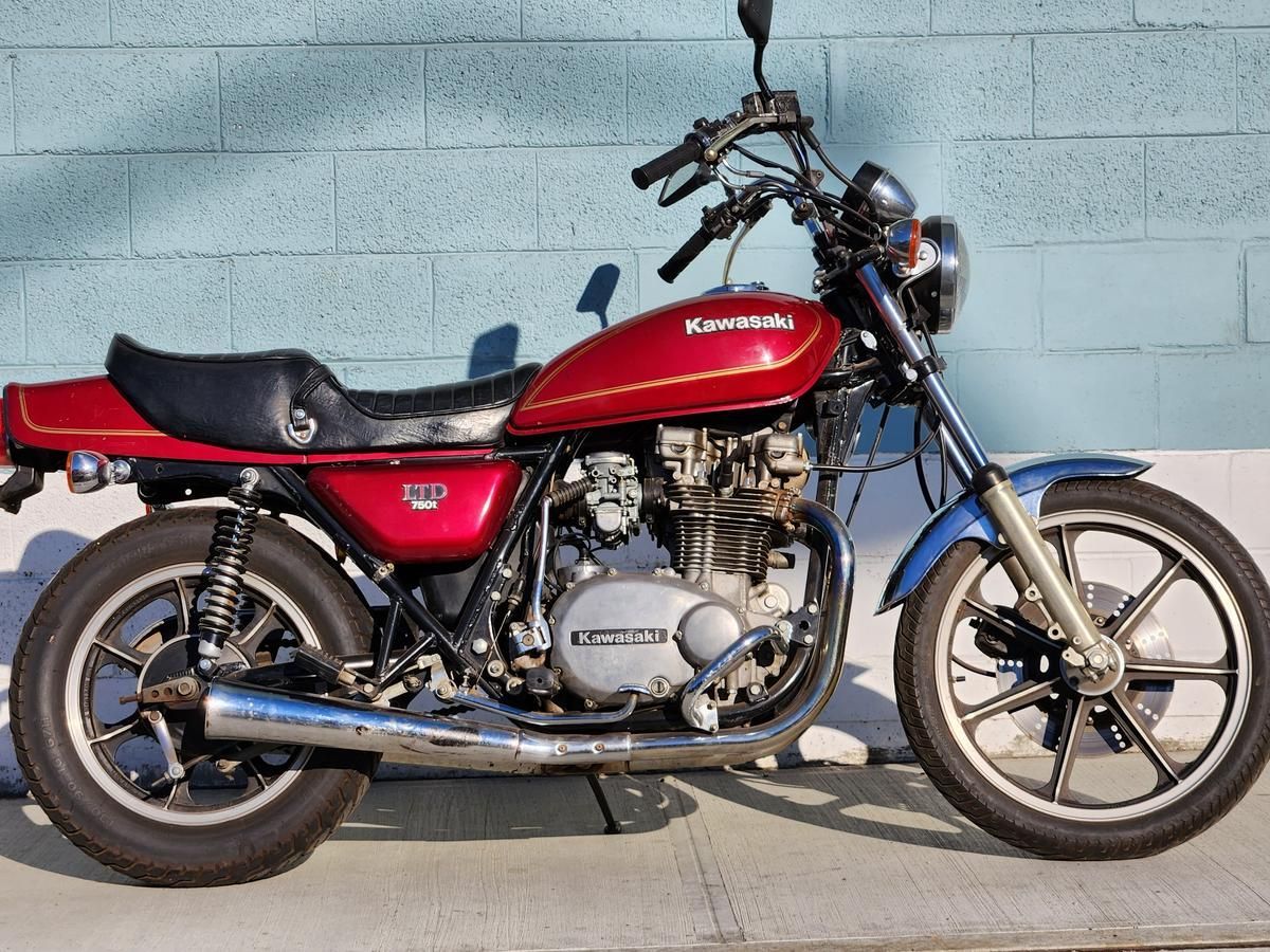 A red kawasaki motorcycle is parked on the sidewalk