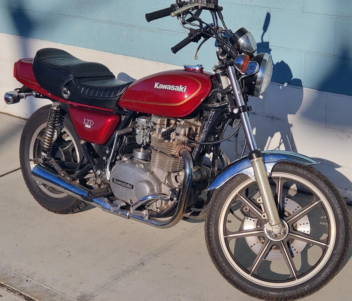 A red kawasaki motorcycle is parked on the sidewalk
