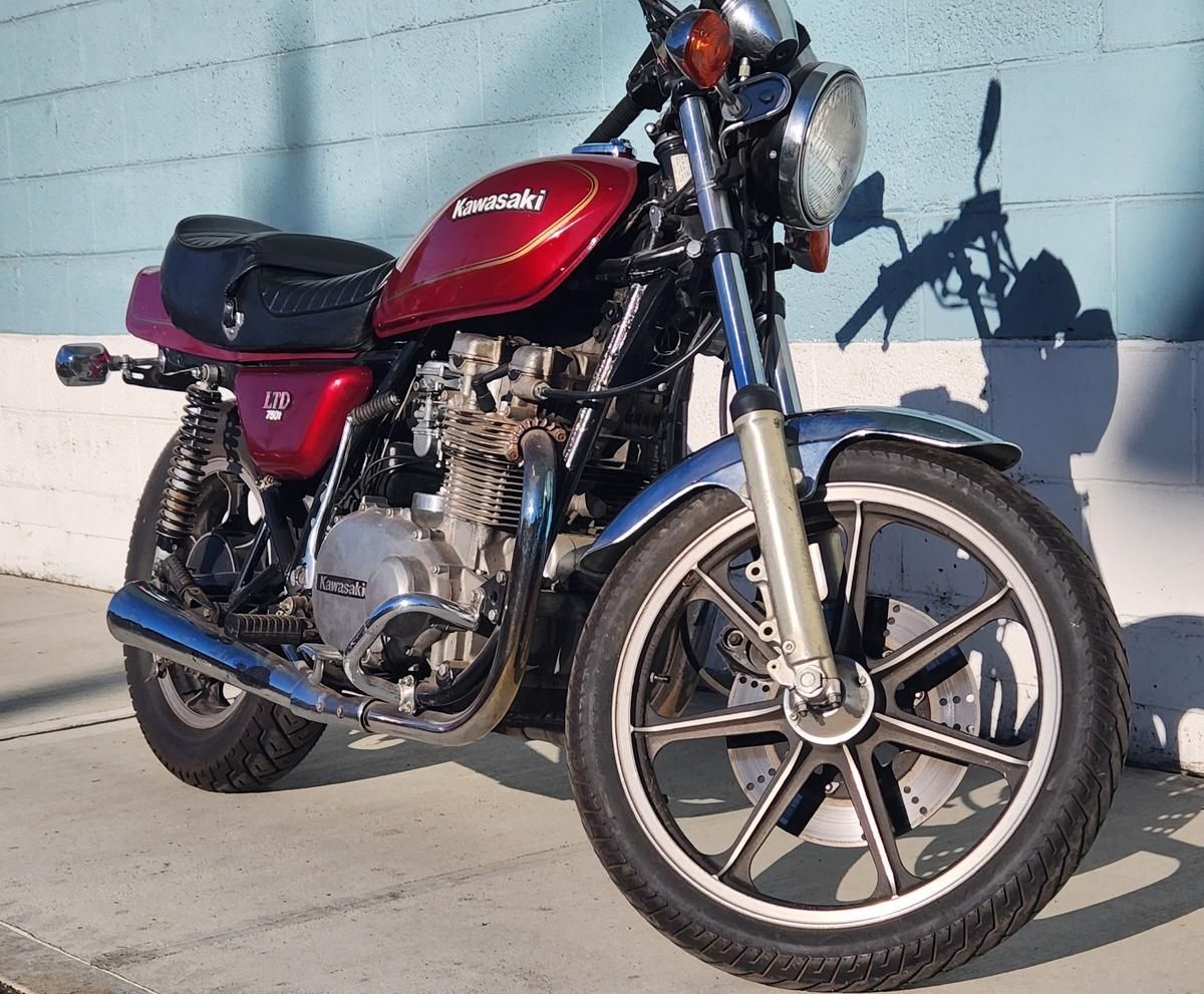 A red kawasaki motorcycle is parked in front of a blue wall