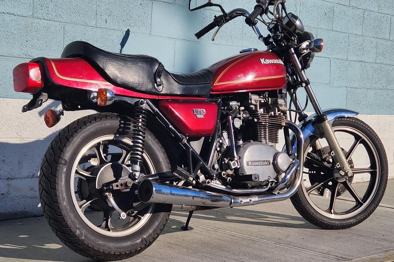 A red kawasaki motorcycle is parked in front of a blue wall