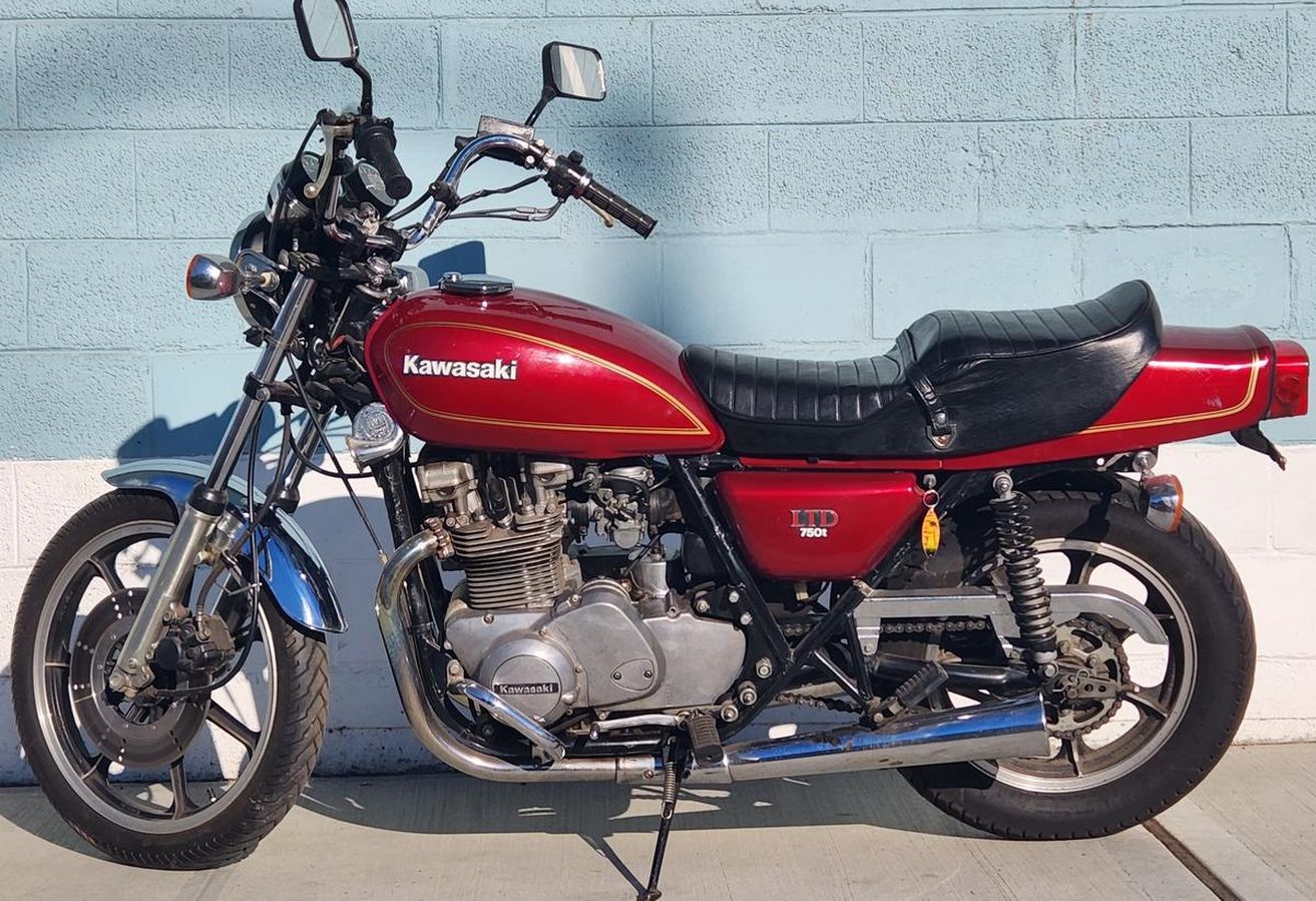 A red kawasaki motorcycle is parked in front of a blue wall