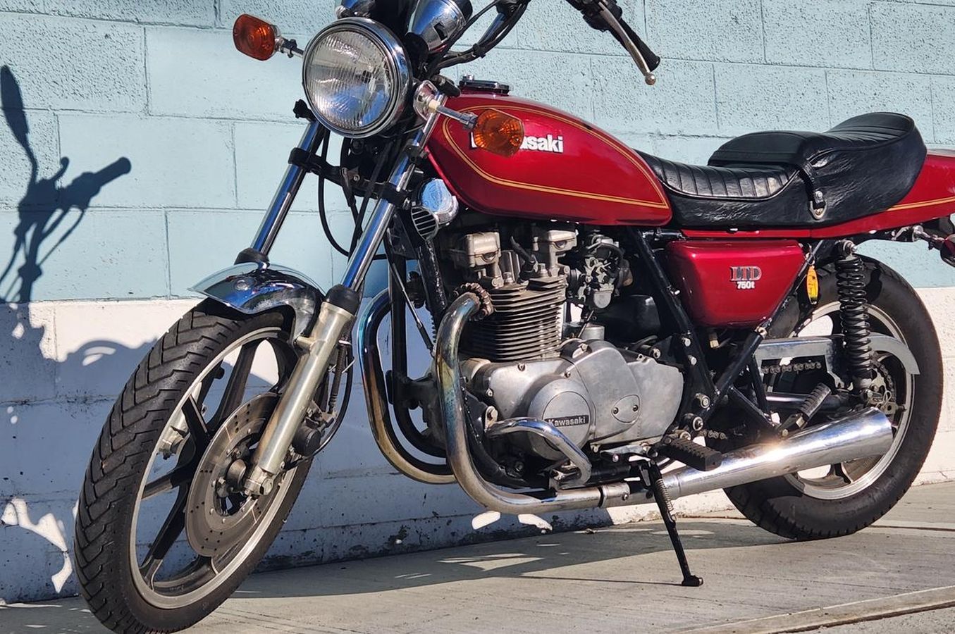 A red motorcycle is parked in front of a blue brick wall.