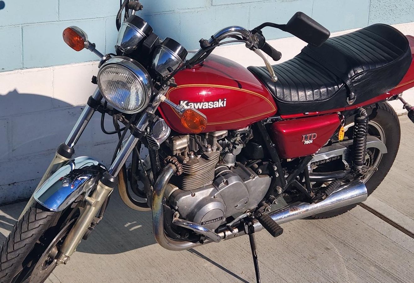 A red kawasaki motorcycle is parked on the sidewalk