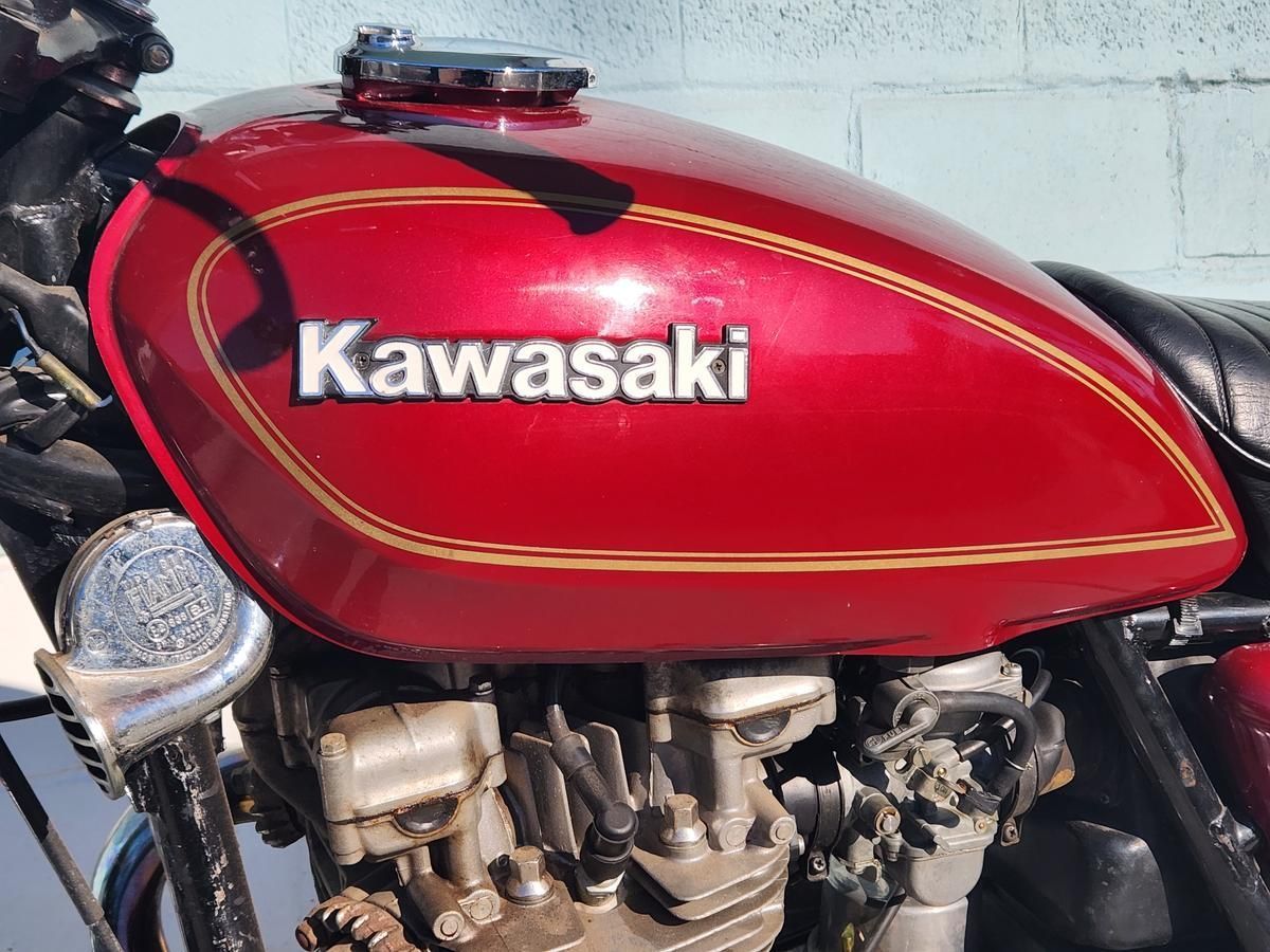 A red kawasaki motorcycle is parked in front of a white wall