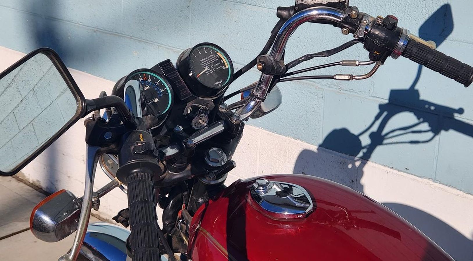 A red motorcycle is parked in front of a blue wall.