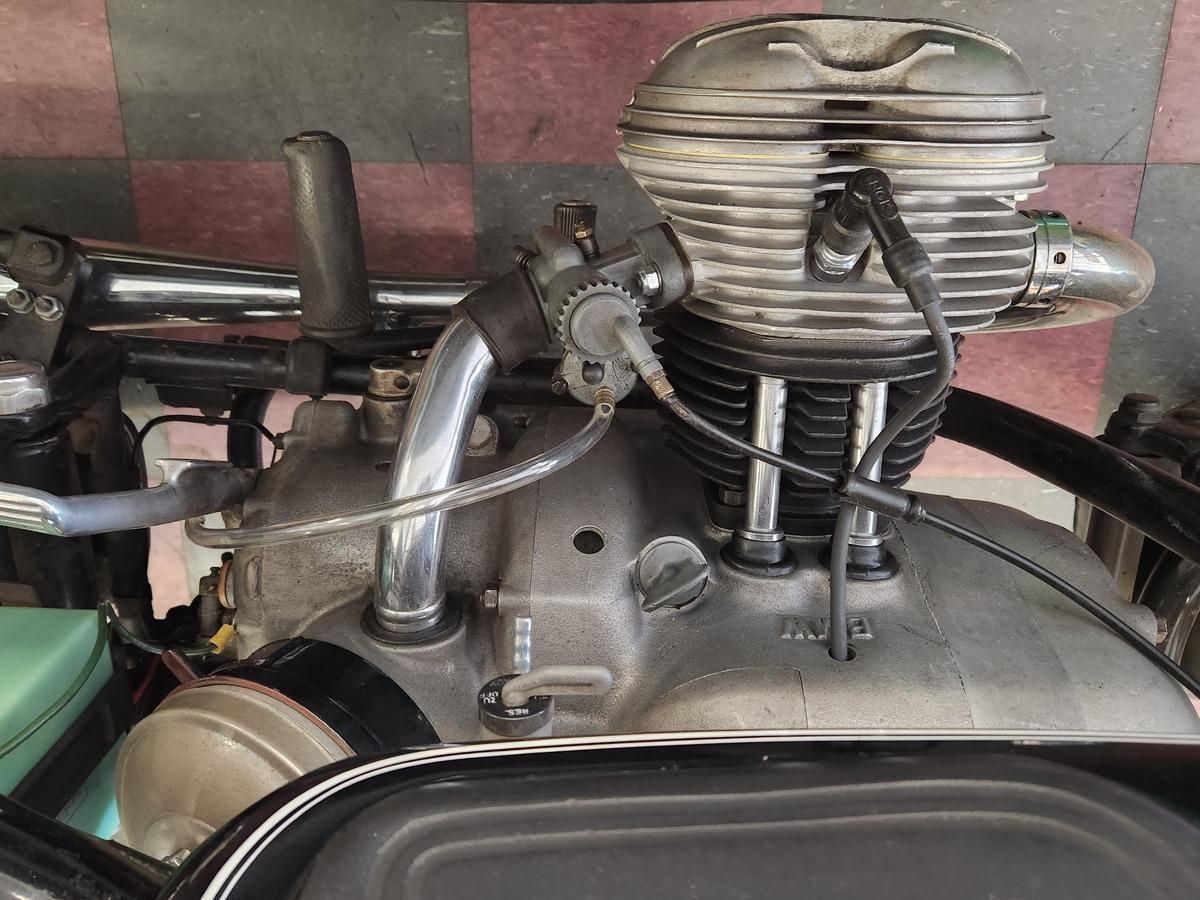 A close up of a motorcycle engine with a checkered floor in the background