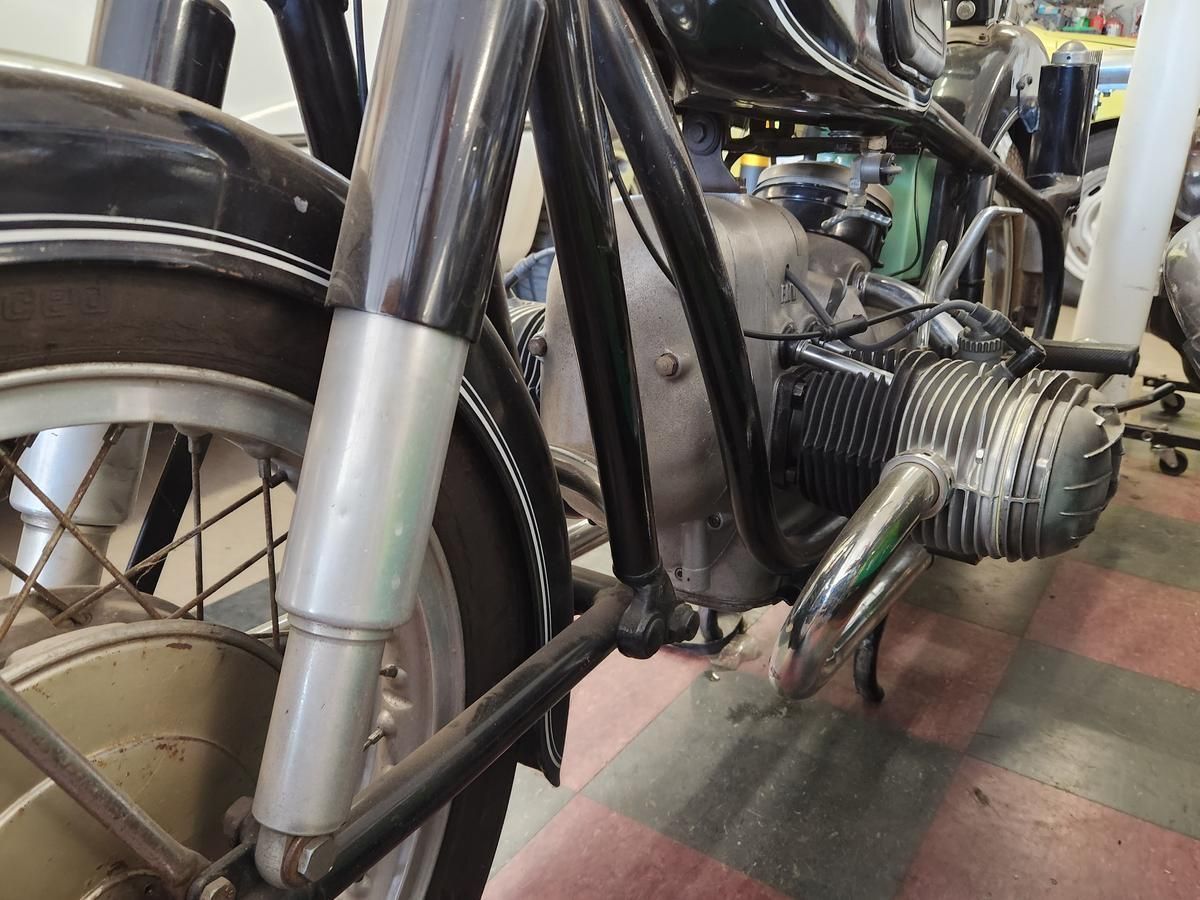 A motorcycle is parked on a checkered floor in a garage.