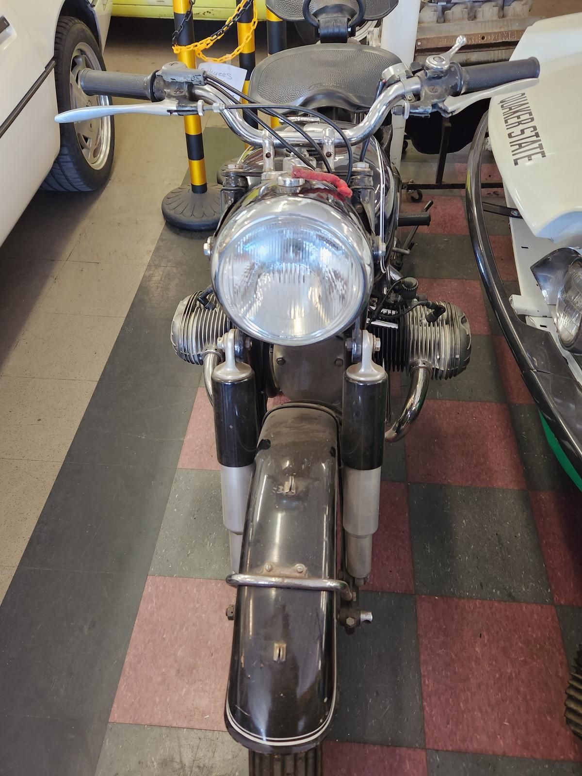 A motorcycle is parked in a garage next to a car