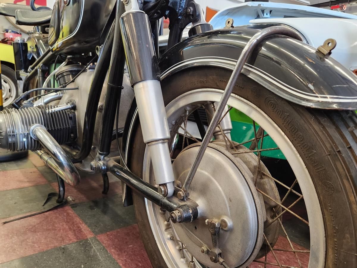 A motorcycle is parked on a checkered floor in a garage.
