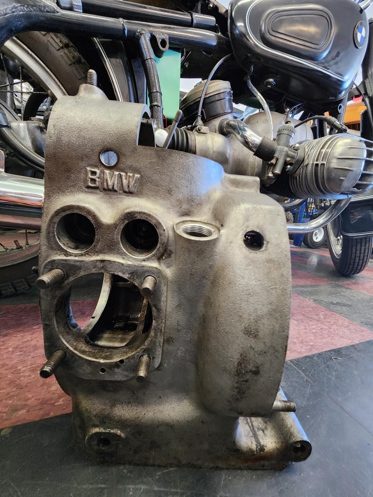 A bmw engine is sitting on the floor next to a motorcycle.