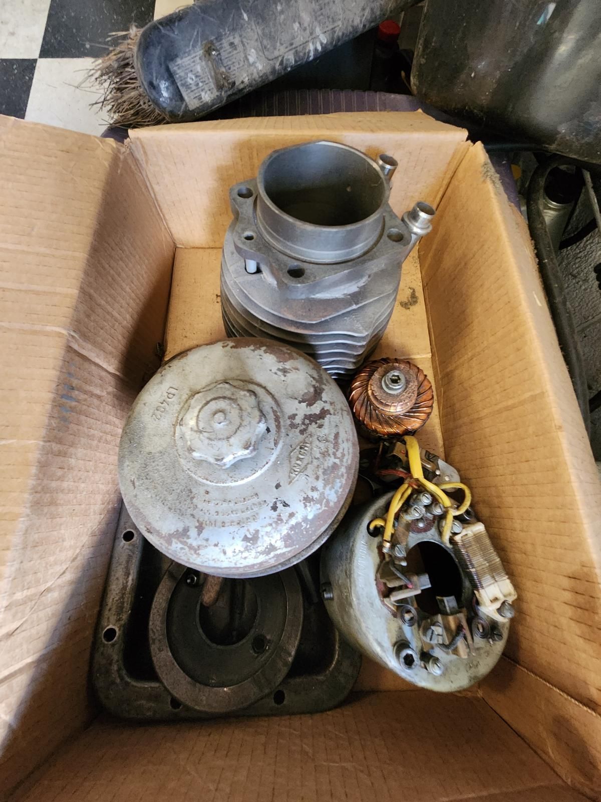 A cardboard box filled with a variety of metal parts.