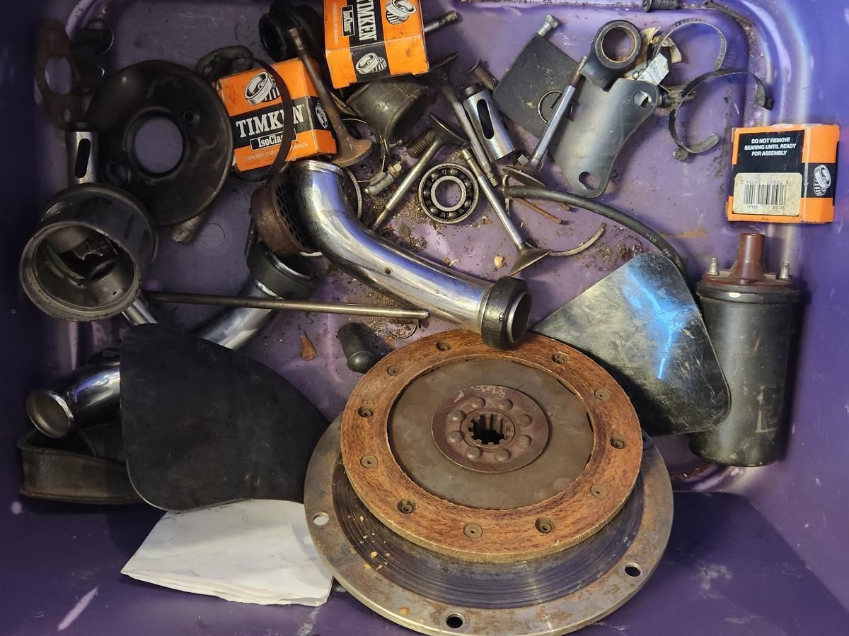 A purple container filled with a bunch of metal parts including a clutch