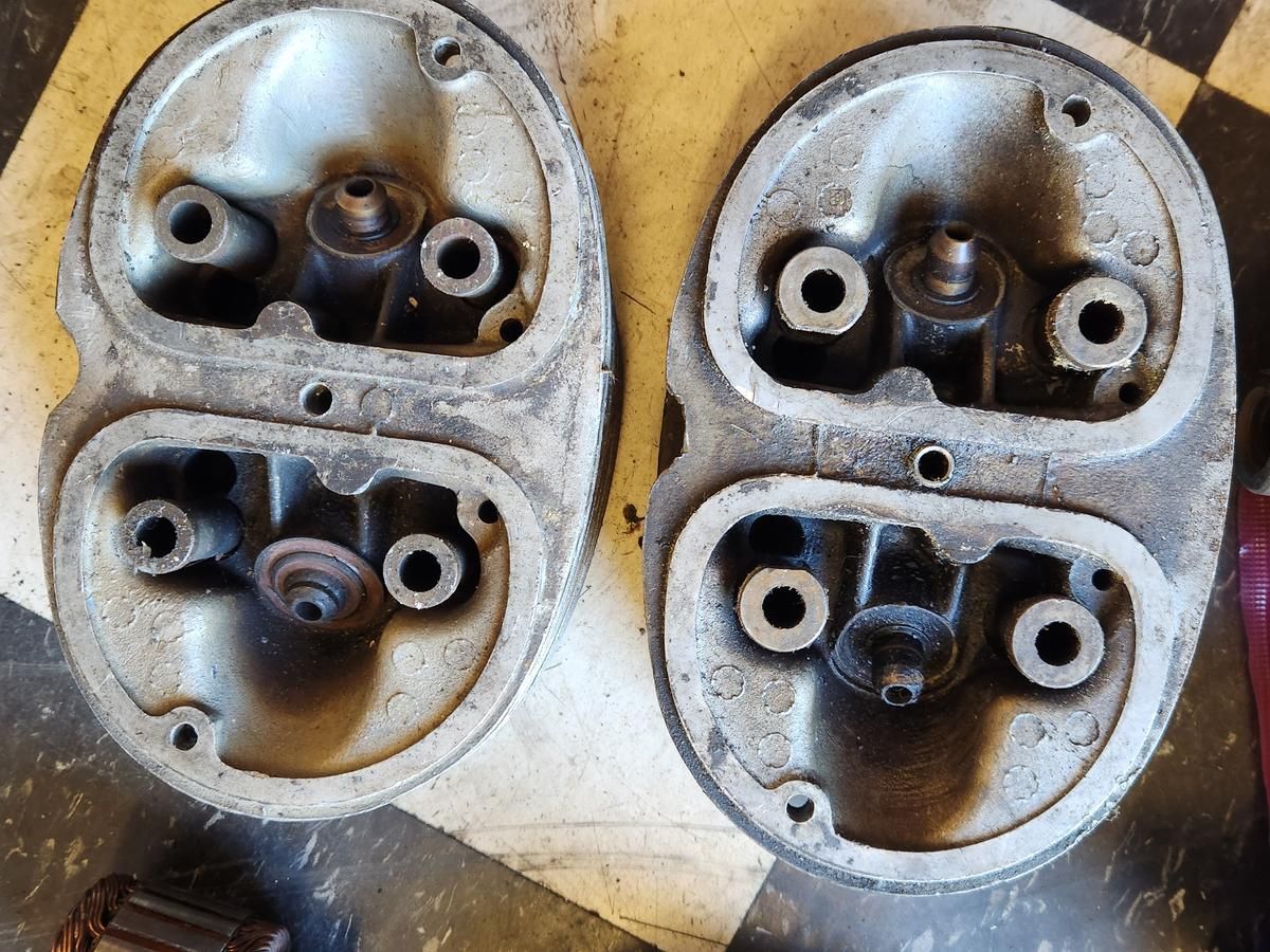 Two cylinder heads are sitting on a checkered floor