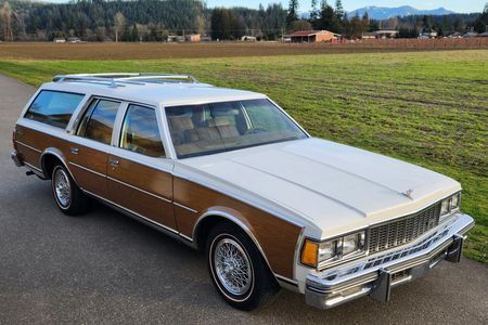 a brown and white station wagon is parked on the side of a road .
