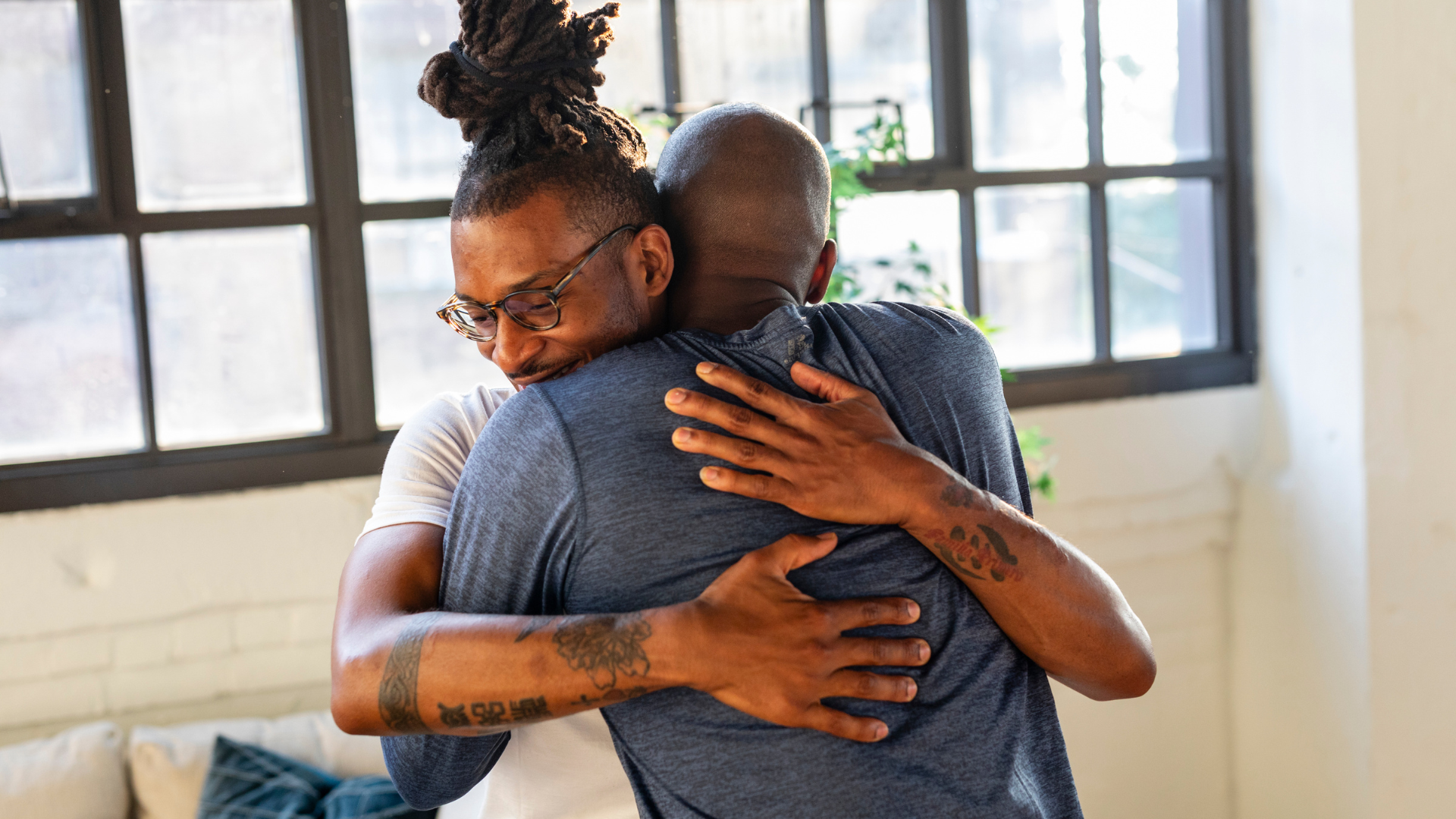 Two men are hugging each other in a living room.