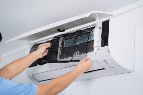 A person is cleaning the filter of an air conditioner
