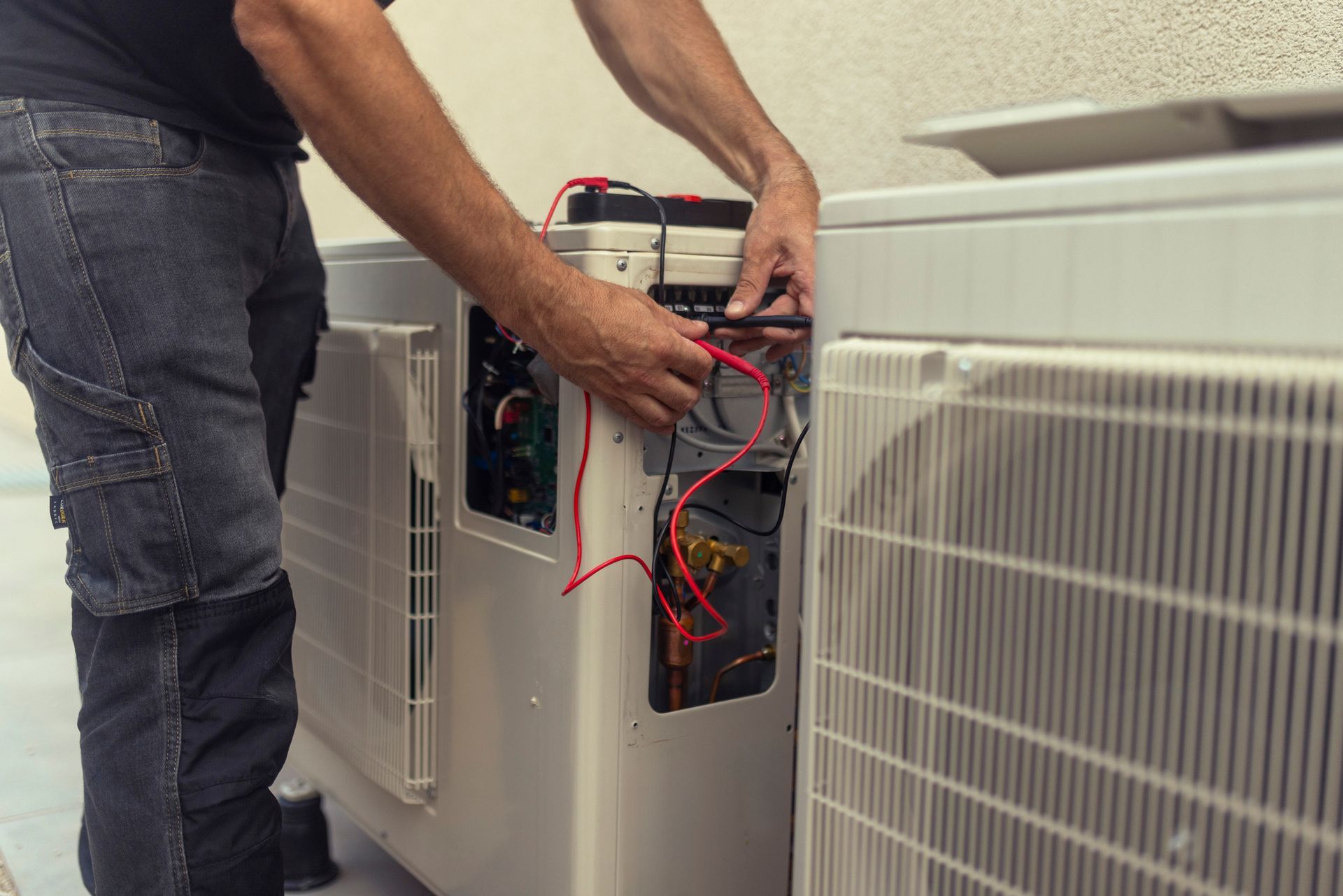 A man is working on an air conditioner outside of a building