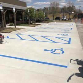 Freshly painted blue handicap parking spaces and striped access aisles on a concrete parking lot surface.