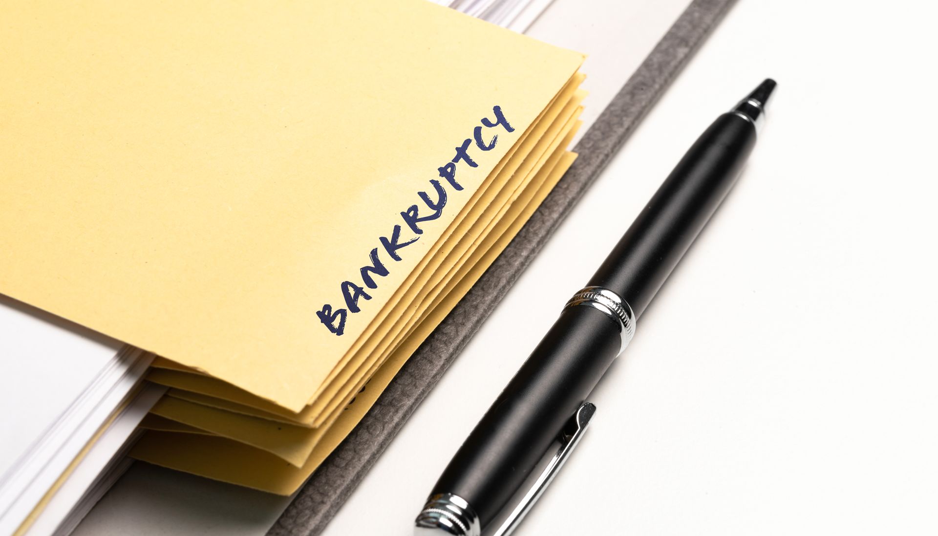 A pen is sitting next to a yellow envelope that says bankruptcy.