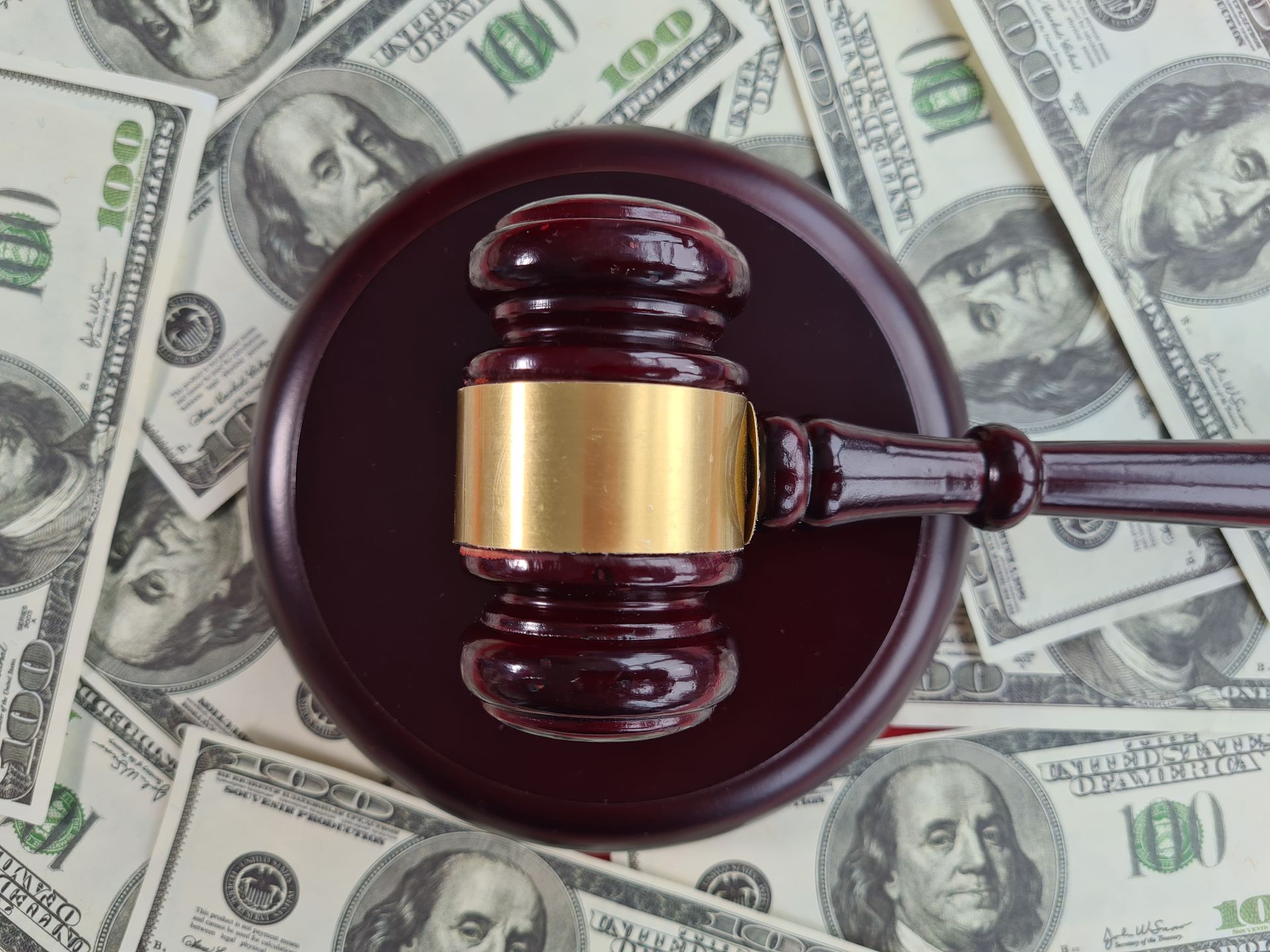 A judge 's gavel is sitting on top of a pile of 100 dollar bills
