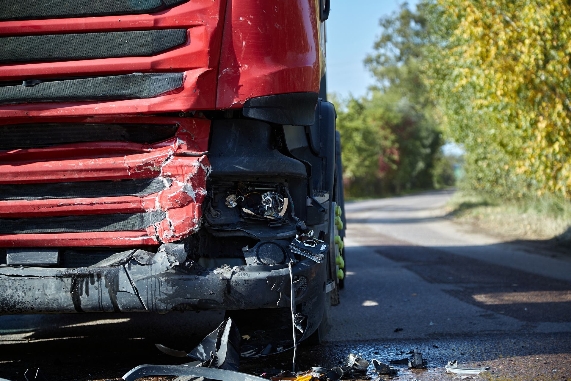 A red truck with a broken bumper is parked on the side of the road.
