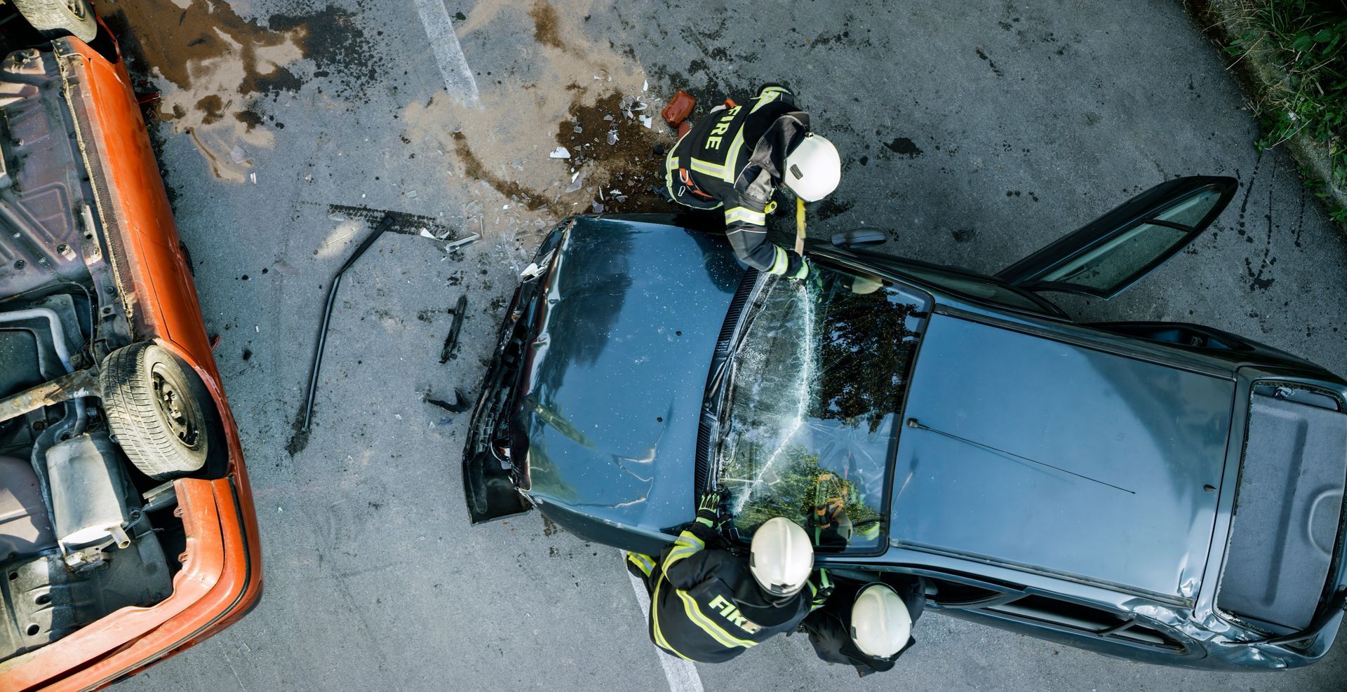 A group of firefighters are standing next to a car that has crashed into another car.