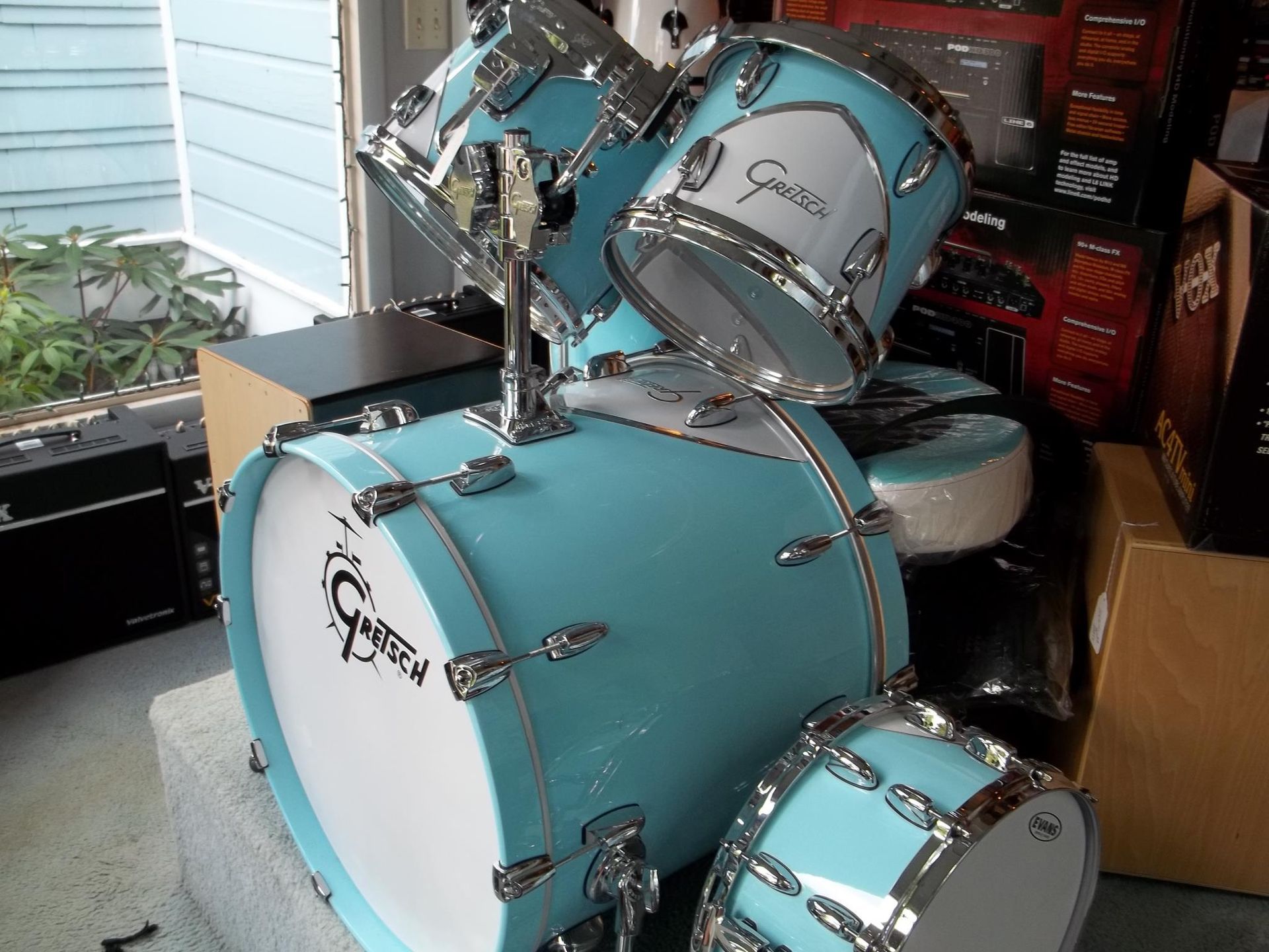 Light blue drum kit with chrome hardware in a cluttered indoor corner