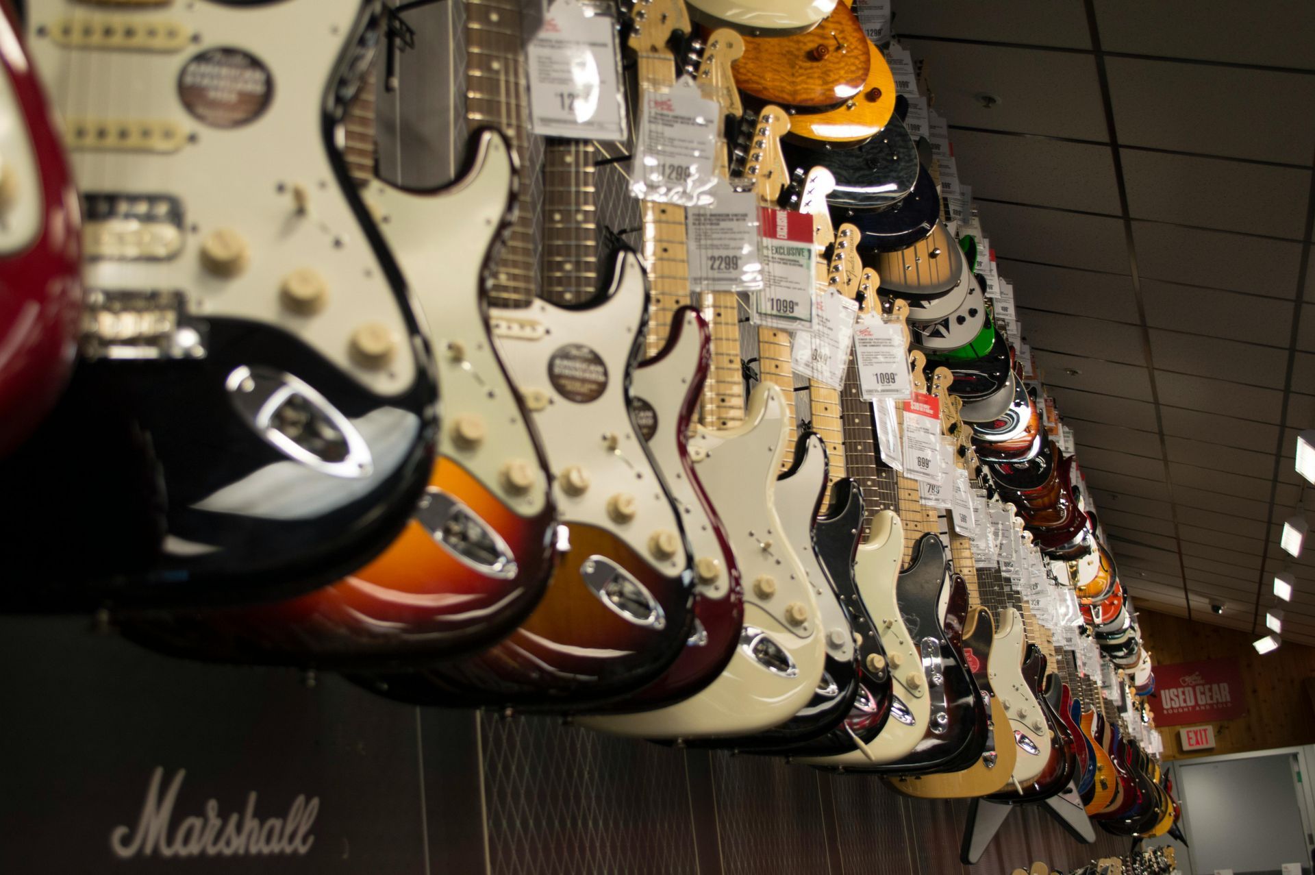 Two electric guitars and amplifiers in a music store display, with a natural wood guitar centered.