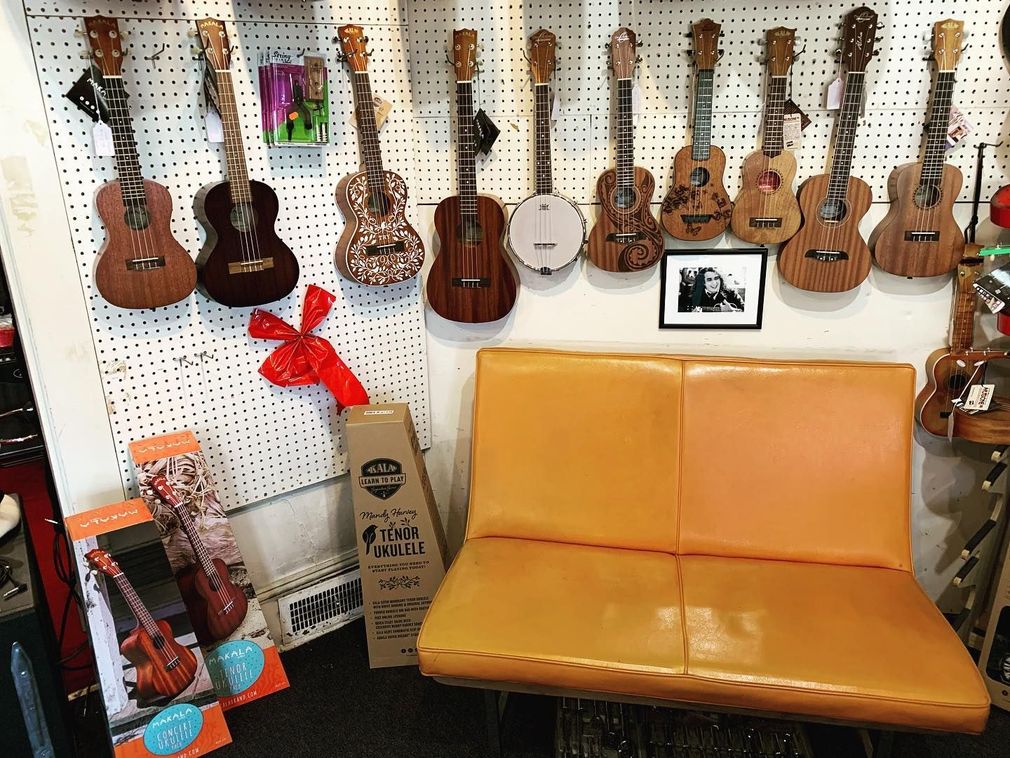 Ukulele display wall with a tan bench and colorful instruments in a music shop