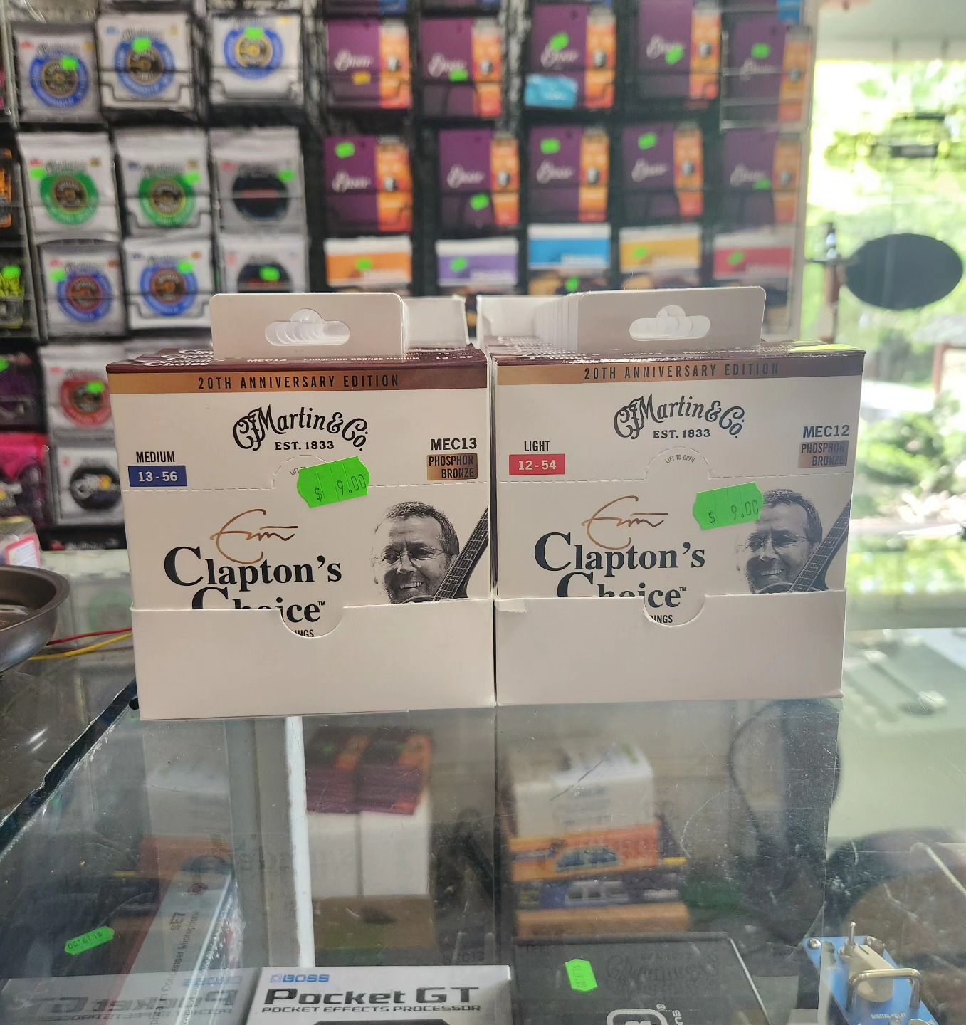 Clapton’s Cuffe boxes on a glass counter in a shop, with colorful product shelves blurred behind.