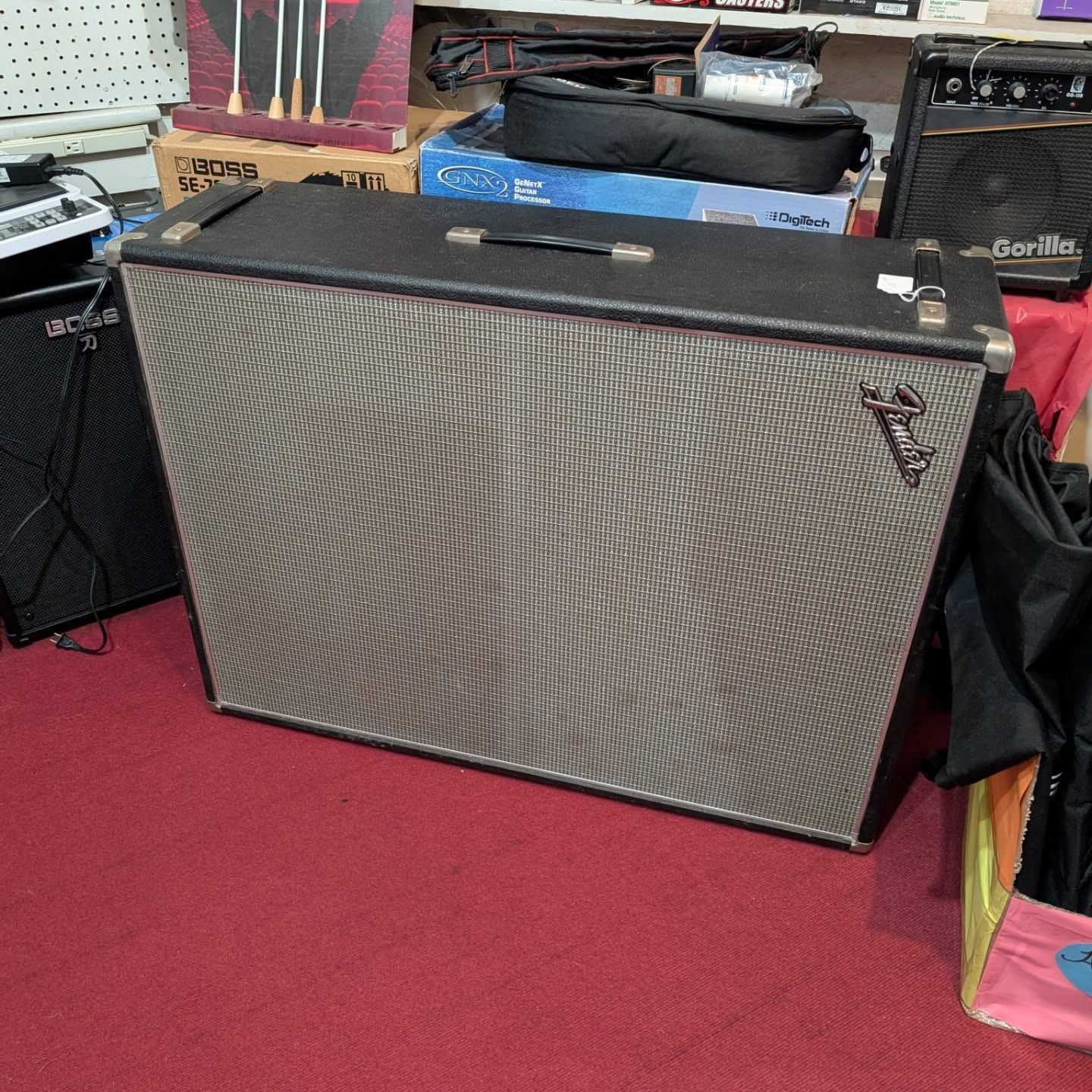 Large silver guitar amplifier on a red carpet in a music shop.