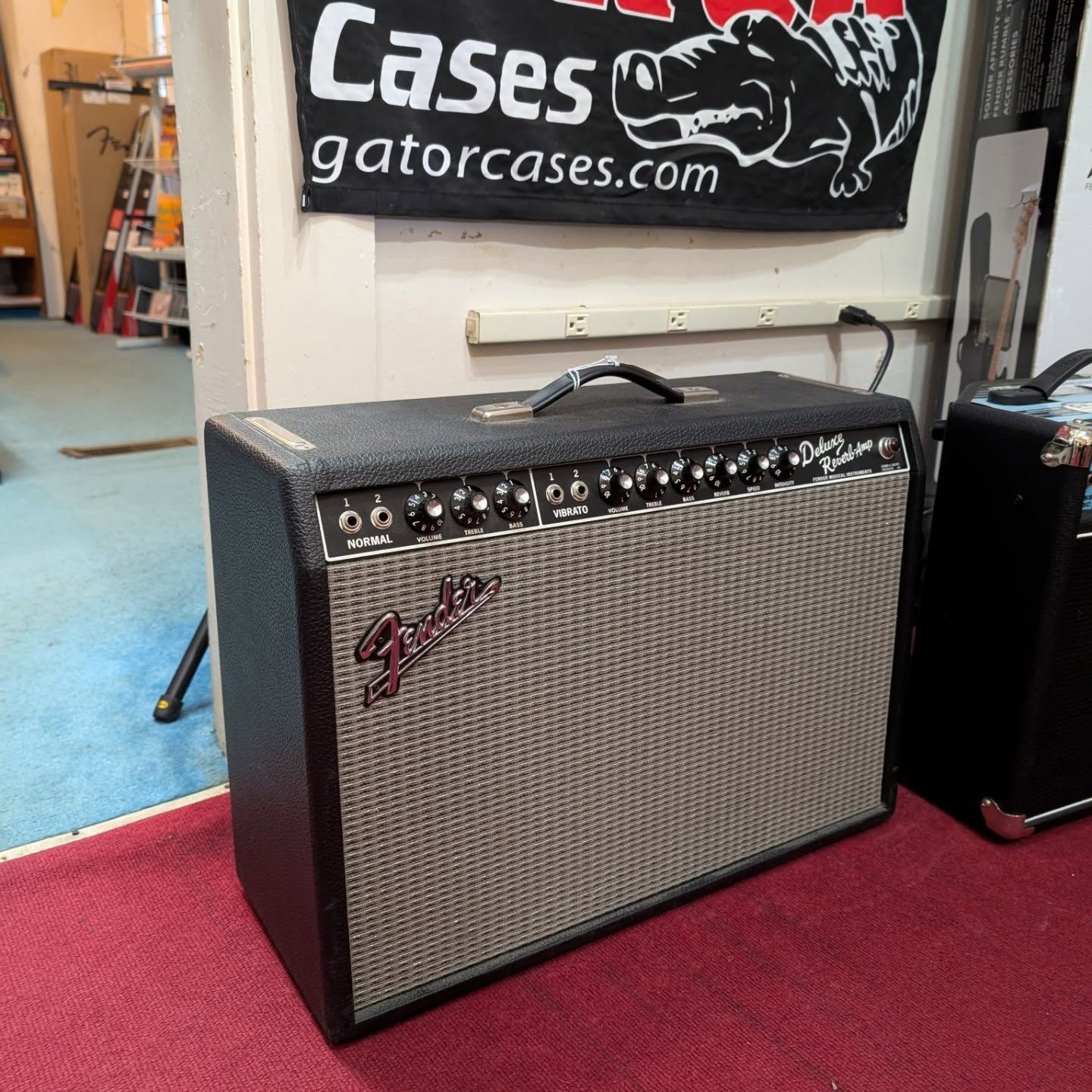 Fender guitar amplifier with silver grille and black trim on red carpet in a shop display area