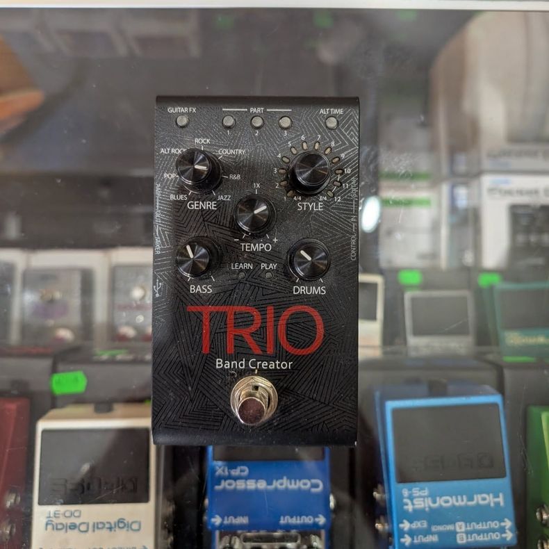 Black TRIO Band Creator guitar effects pedal with knobs, hanging in a shop display.