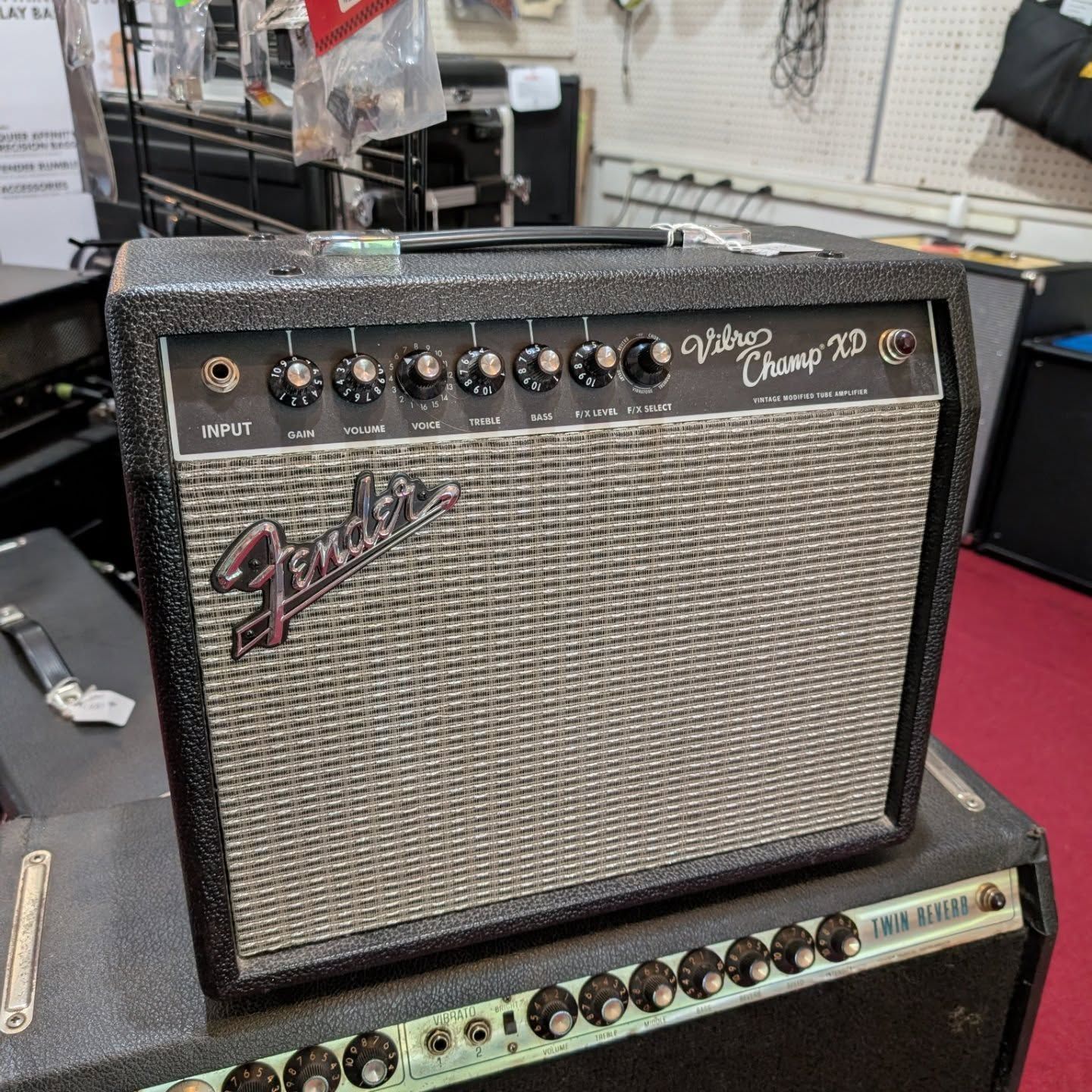 Fender Champ 20 guitar amplifier with silver grille and black control panel on a shop counter.